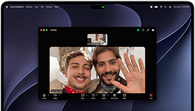 Egy ezüstszínű MacBook Pro PROLED XDR-kijelzőjén egy videohívás látható, amelyben két ember egy napfényes városból integet egy otthonában lévő harmadik embernek.