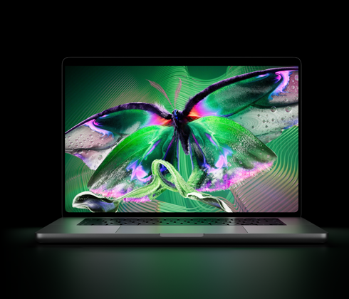 Egy kinyitott asztrofekete MacBook Pro PROLED XDR-kijelzője élénk színekkel teli, részletgazdag, nagy kontrasztú videót jelenít meg, a fénye a billentyűzetre vetül.