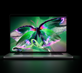 Egy kinyitott asztrofekete MacBook Pro PROLED XDR-kijelzője élénk színekkel teli, részletgazdag, nagy kontrasztú videót jelenít meg, a fénye a billentyűzetre vetül.