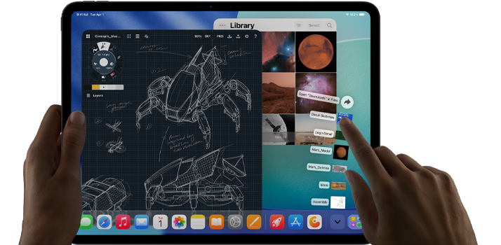 Asztrofekete iPad Pro, a felhasználó bal kézzel tartja a készüléket, jobb kézzel pedig mutató mozdulattal kezeli a megnyitott alkalmazásablakokat, melyek között megjelenik egy rajzolóapp vázlatos gépészeti tervekkel, fotókönyvtár bolygókkal és az űrről készült képekkel, valamint a Letöltések mappa fájljai legyezőszerűen kitárva