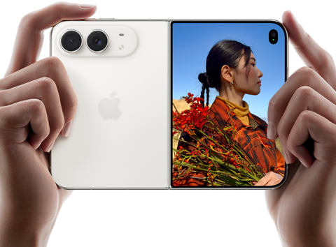 Vízszintes tájolású iPhone csillagfehér színben, két kézben tartva, kinyitva, a bal oldali panelen a 48 MP Dual Fusion hátlapi kamerák, a jobb oldali panelen egy külső kijelzőn fotózkodó ember, aki felvételkészítés közben láthatja a saját arcát a Duo Preview funkcióval.