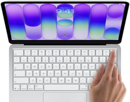 MacBook Neo ezüstszínben, a kijelzőn a bejelentkezési képernyő, egy ember ujja a billentyűzet jobb felső sarkában található Touch ID érzékelőn
