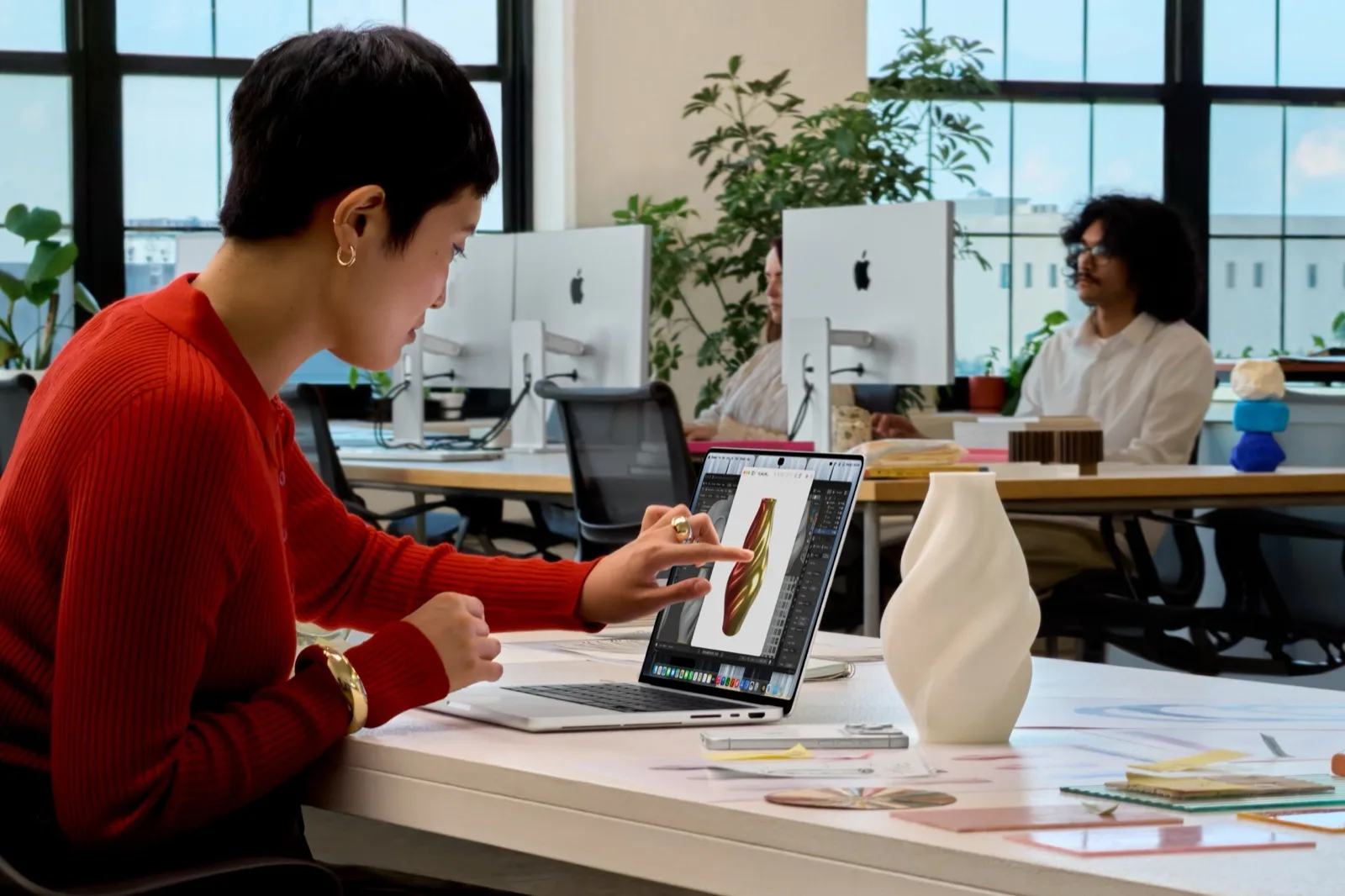 Nő egy irodában ujjal szerkeszt egy képet a MacBook Pro kijelzőjén